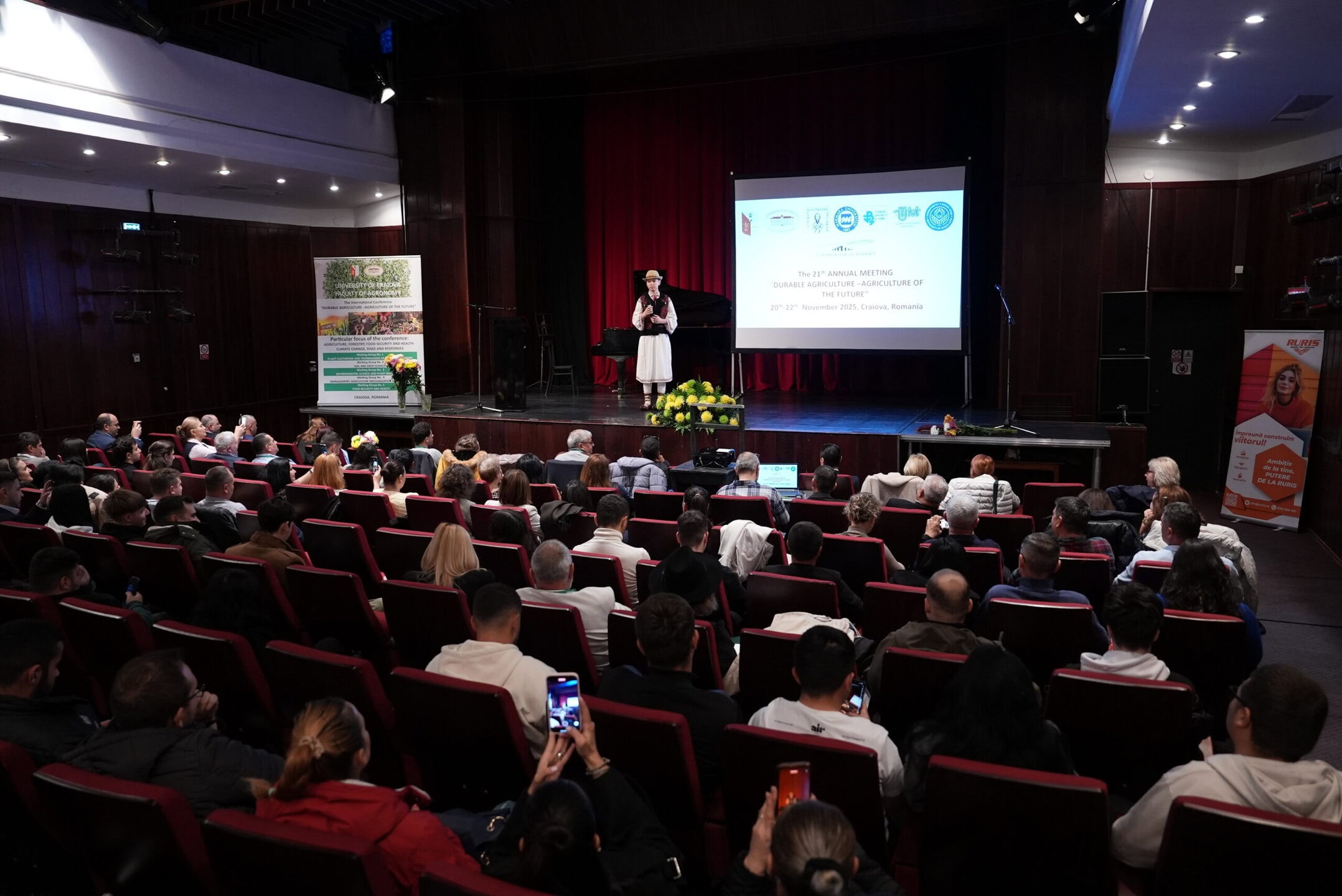 Speaker in traditional robe on stage during the University of Craiova Faculty of Agronomy ACROSS – European University conference.