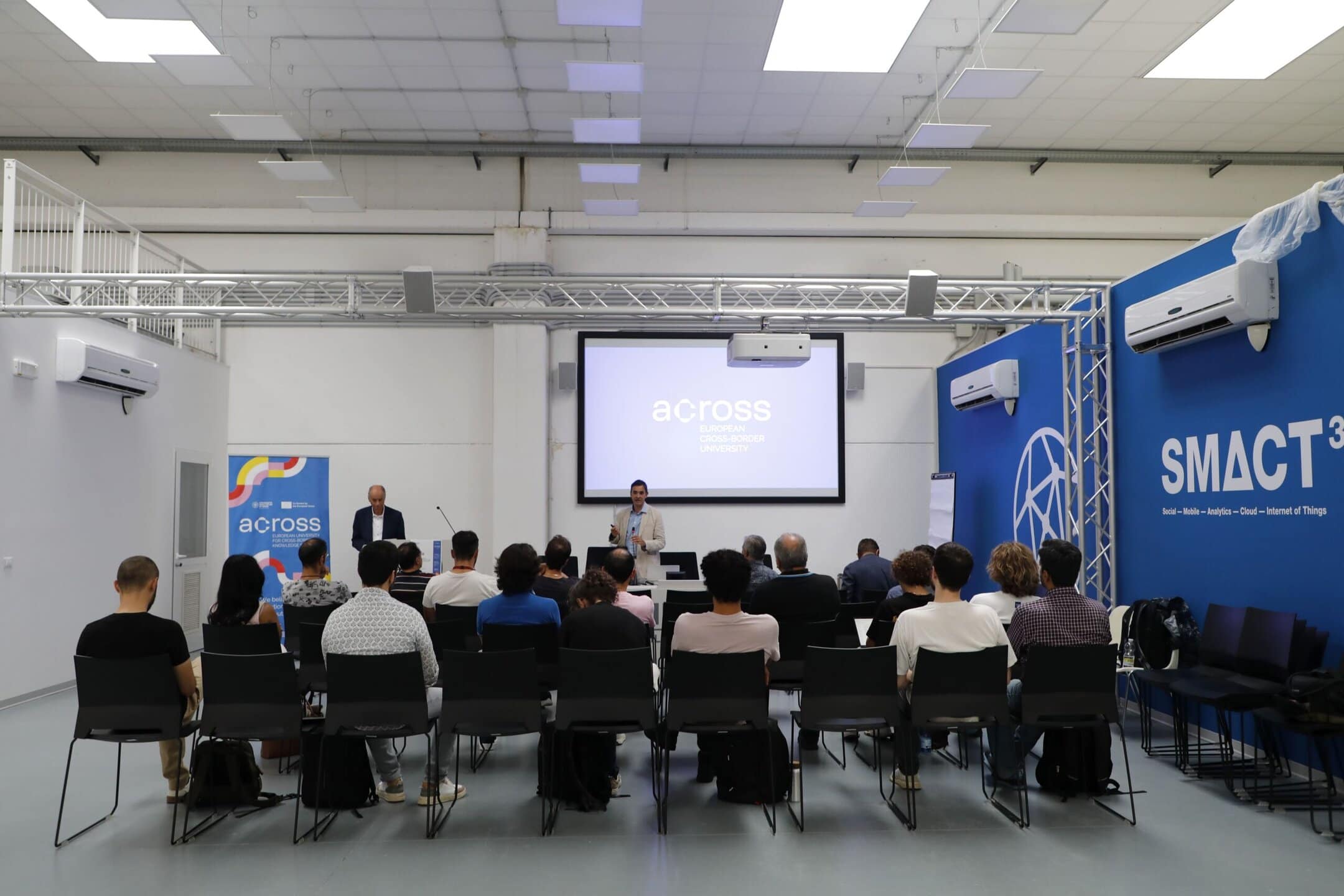 Participants seated in a lecture room at the University of Udine, including scientists and entrepreneurs, attentively listening to a speaker during an event of the Across – European Cross-Border University.